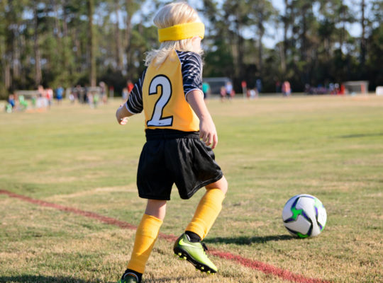 kid playing soccer on a youth sports team in the spring or summer.