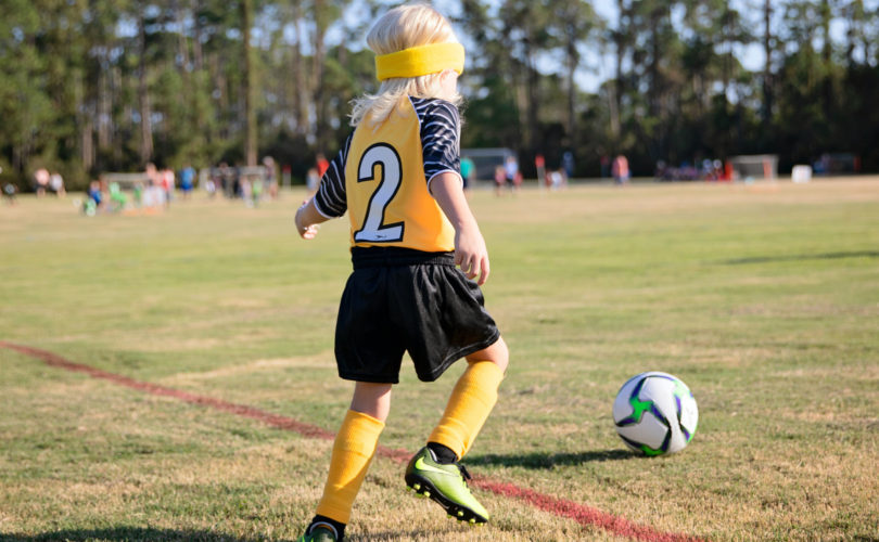 kid playing soccer on a youth sports team in the spring or summer.