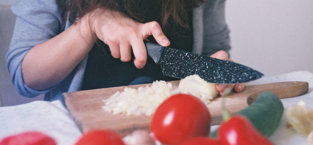woman holding knife dangerously cutting vegetables