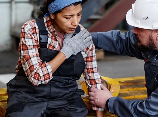 woman with dislocated shoulder getting help from coworker.