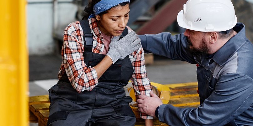 woman with dislocated shoulder getting help from coworker.
