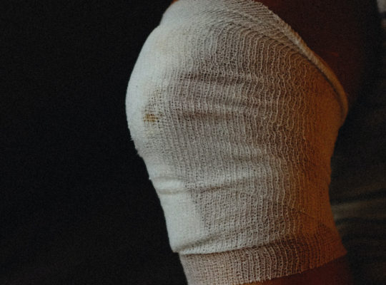 injured knee wrapped in a triangular bandage gauze