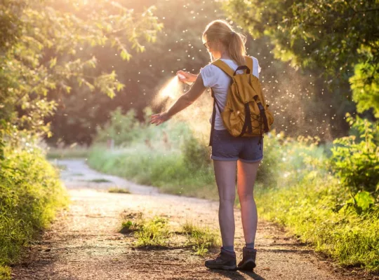 insects swarming around a woman spraying while hiking.