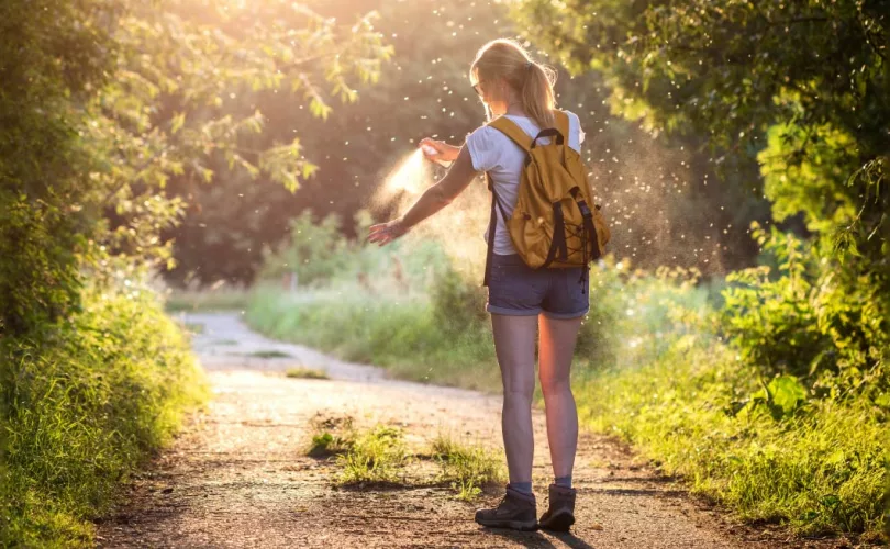 insects swarming around a woman spraying while hiking.