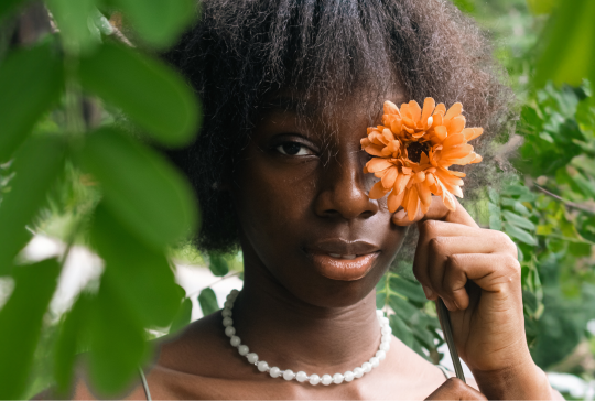Girl Covering her eye with a flower hiding her stye on her eye.
