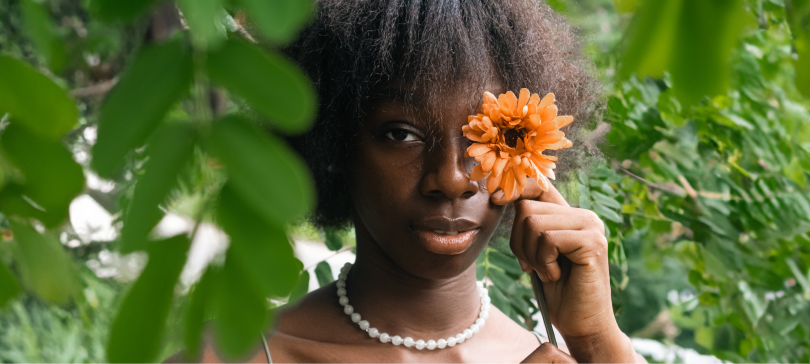 Girl Covering her eye with a flower hiding her stye on her eye.